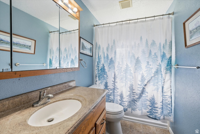 1095 Park Avenue Logan, UT 84321 - Photo 10 of 27 Full bath featuring a textured wall, vanity, light tile patterned floors, a textured ceiling, and shower / tub combo with curtain