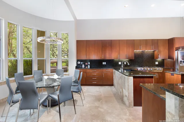 a kitchen with stainless steel appliances granite countertop a stove a sink a microwave a dining table and chairs