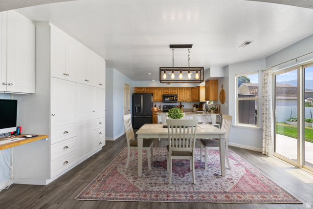 1393 West 150 North Springville, UT 84663 - Photo 8 of 31 Open-concept dining and kitchen area featuring wood-finish flooring, white built-in cabinetry, a linear chandelier, and a sliding glass door leading to the exterior