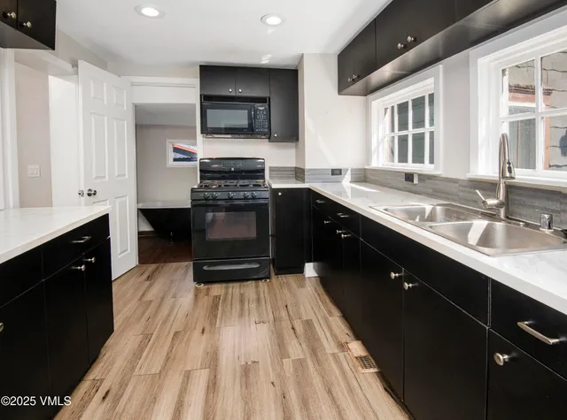 a kitchen with a sink wooden floor and stainless steel appliances