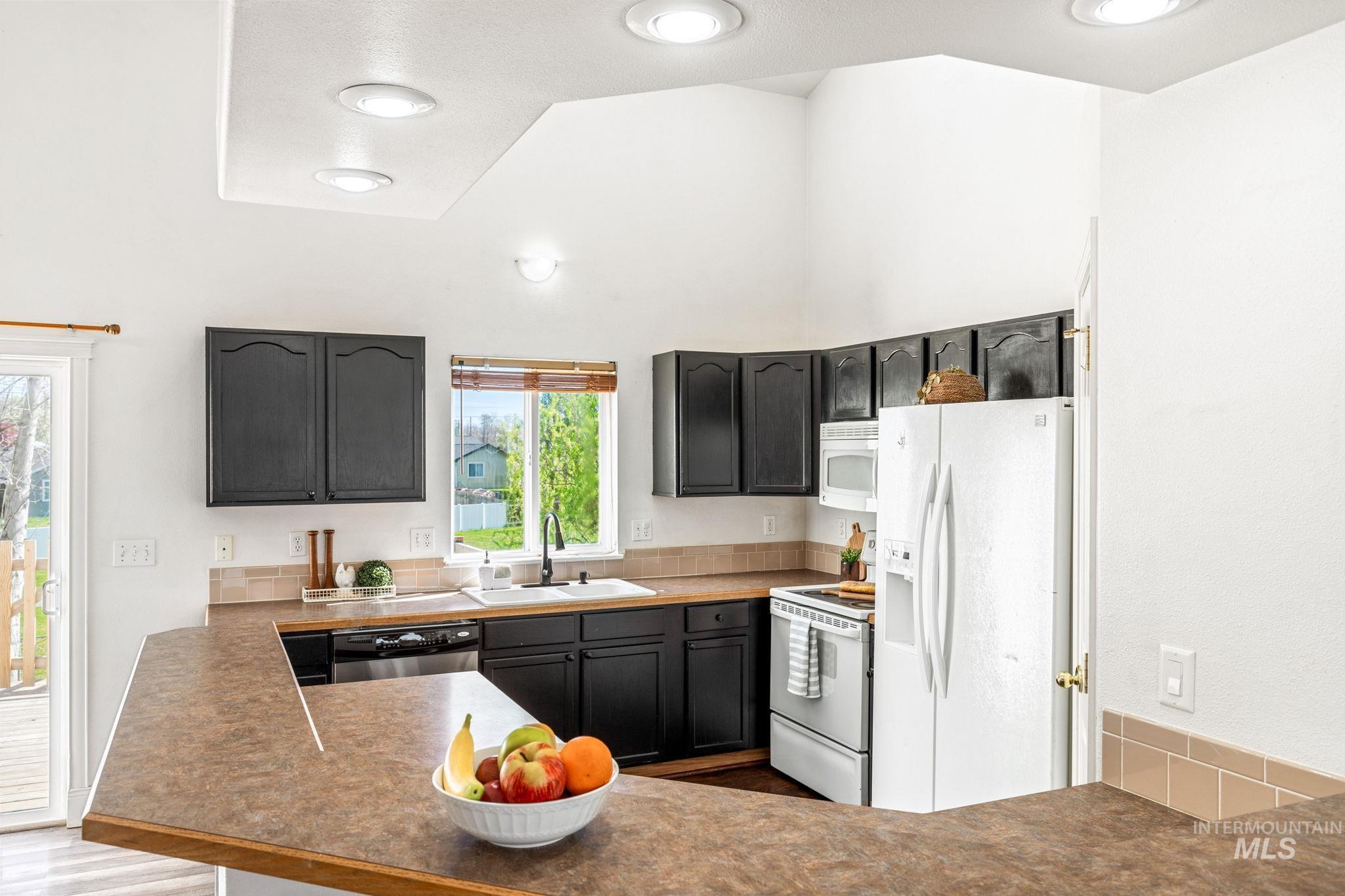 526 Cornwall Way Fruitland, ID 83619 - Photo 13 of 42 Kitchen featuring white appliances, a peninsula, dark countertops, and dark cabinetry
