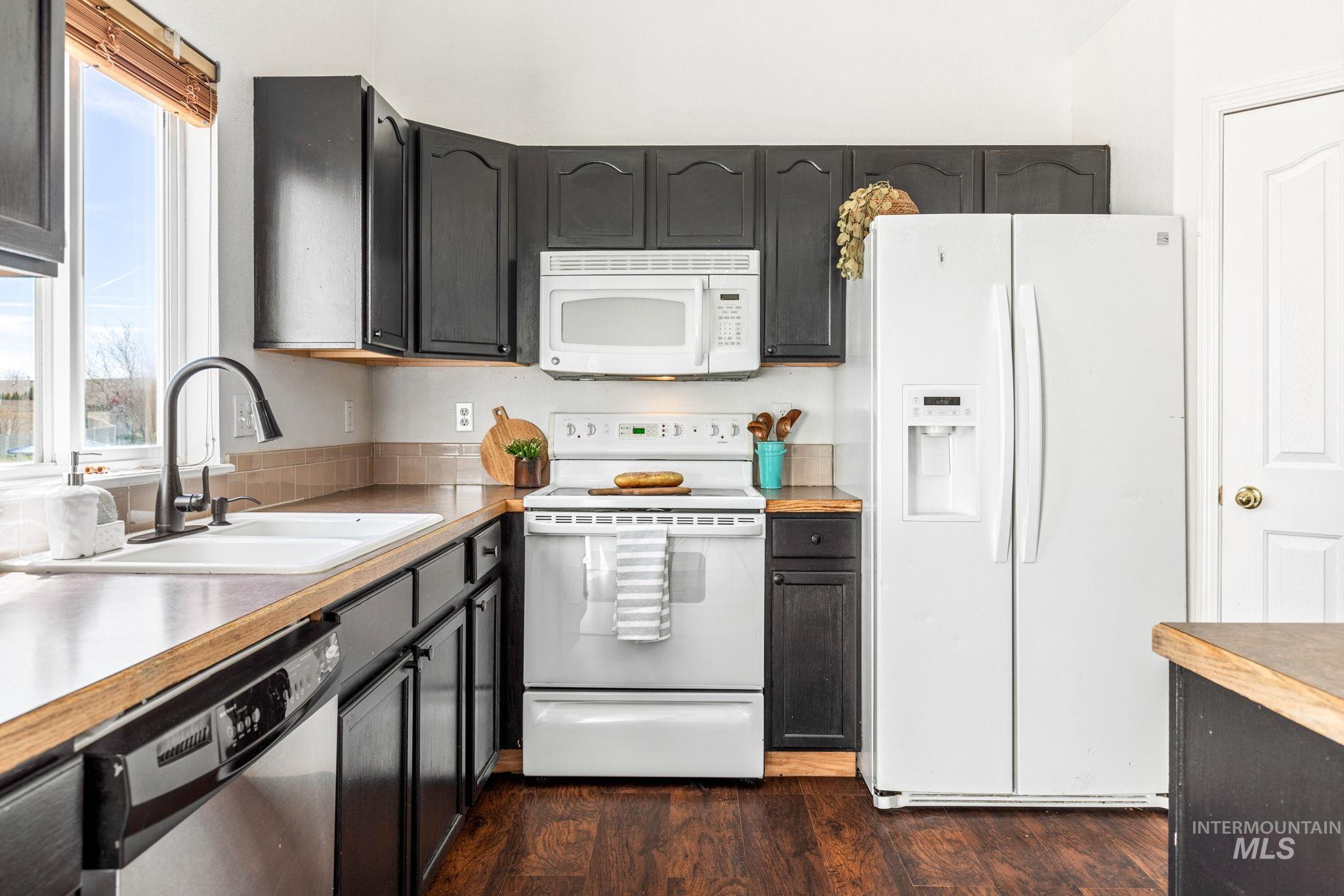 526 Cornwall Way Fruitland, ID 83619 - Photo 14 of 42 Kitchen with white appliances, dark wood-style flooring, light countertops, and dark cabinetry