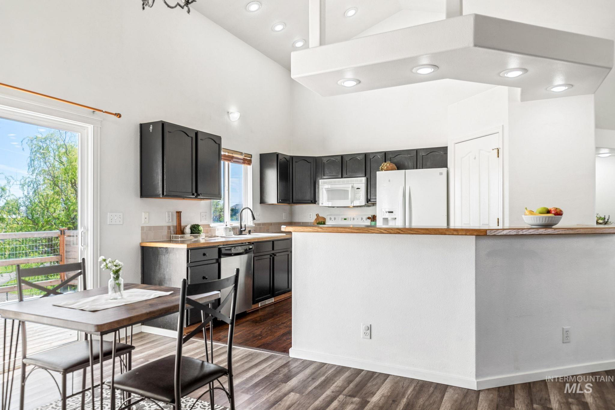 526 Cornwall Way Fruitland, ID 83619 - Photo 10 of 42 Kitchen with white appliances, dark wood-style floors, a high ceiling, dark cabinetry, and recessed lighting