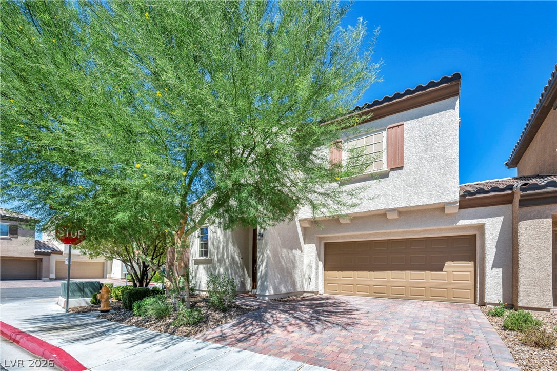 5014 Fiery Sky Ridge Street Las Vegas, NV 89148 - Photo 2 of 21 A Mediterranean-inspired facade with terracotta roof tiles and an inviting brick paver driveway awaits.