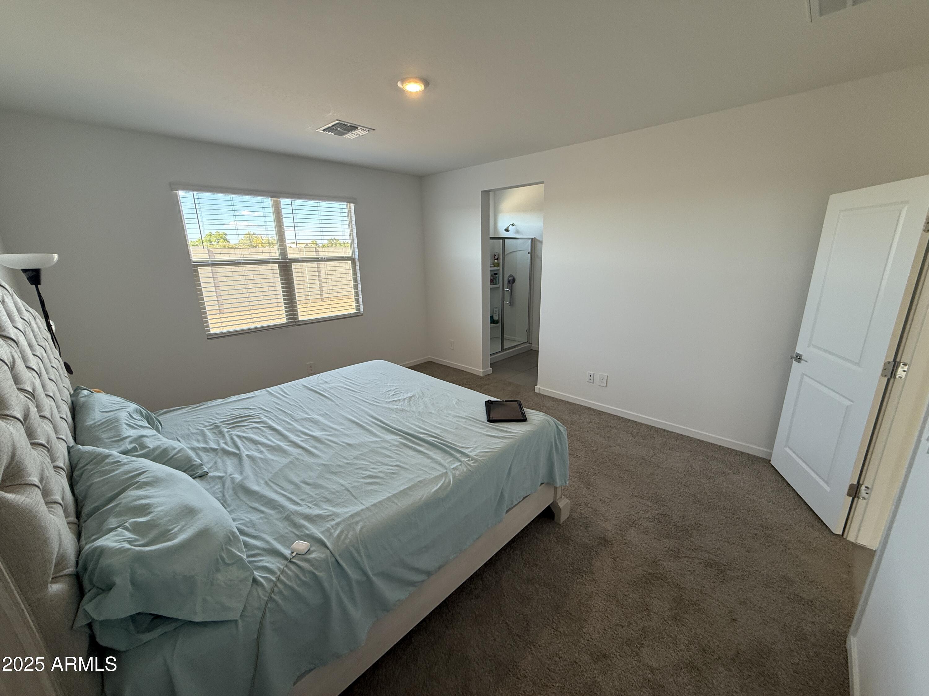 8534 West Warner Street Tolleson, AZ 85353 - Photo 14 of 36 a bed sitting in a bedroom next to a window