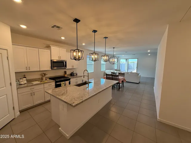 a large white kitchen with a stove a sink dishwasher and a refrigerator with wooden floor