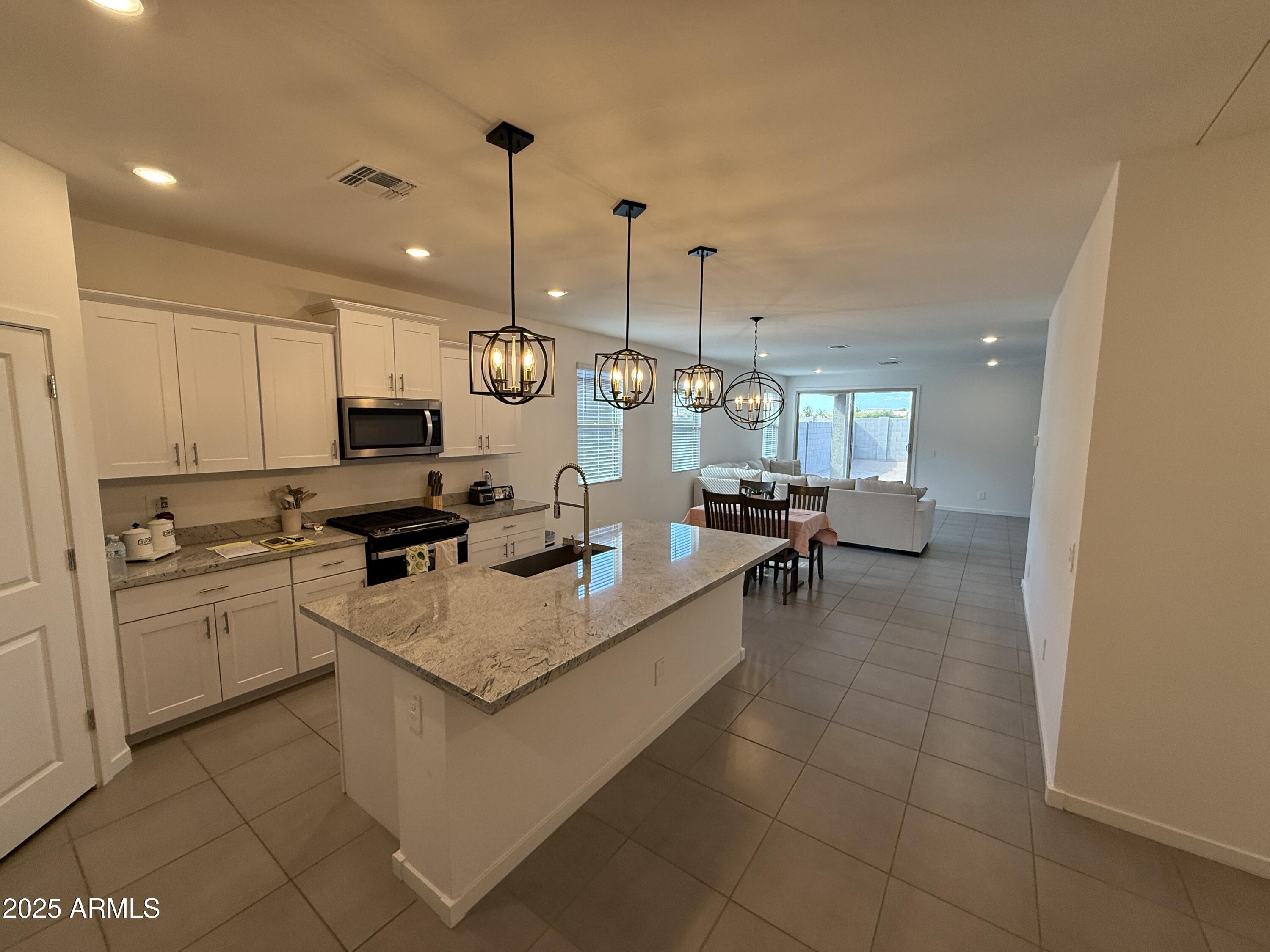 8534 West Warner Street Tolleson, AZ 85353 - Photo 4 of 36 a large white kitchen with a stove a sink dishwasher and a refrigerator with wooden floor