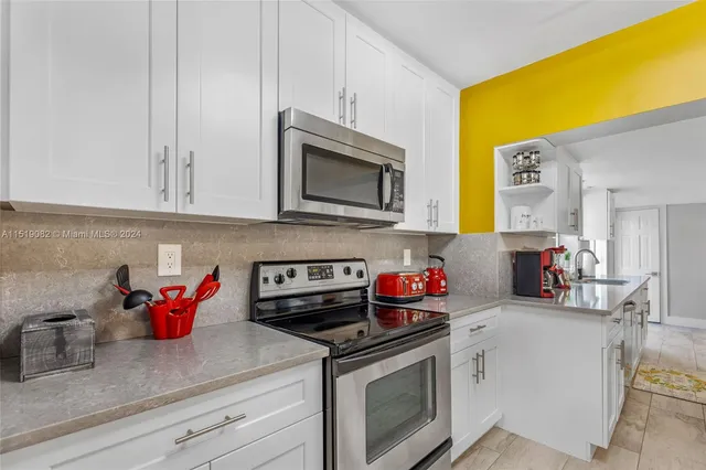 a kitchen with stainless steel appliances granite countertop a sink dishwasher stove and white cabinets