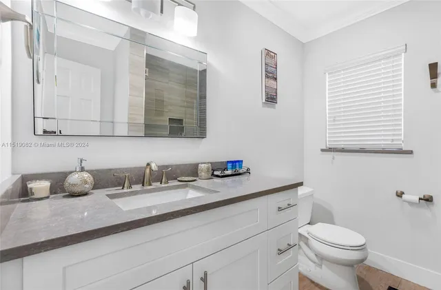 a bathroom with a granite countertop toilet sink and mirror