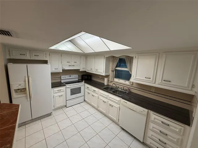 a kitchen with granite countertop white cabinets and white appliances