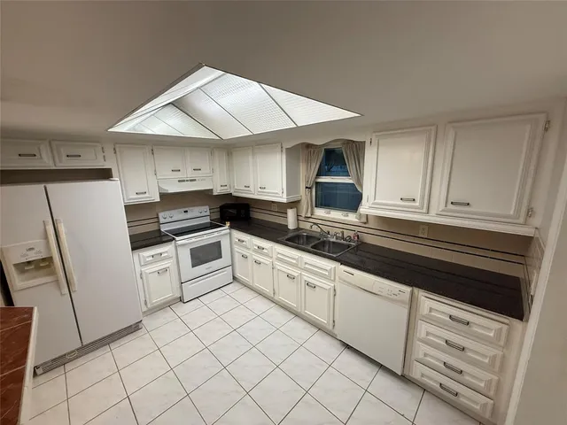 a kitchen with stainless steel appliances granite countertop a sink stove refrigerator and cabinets