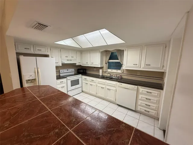 a kitchen with white cabinets and sink