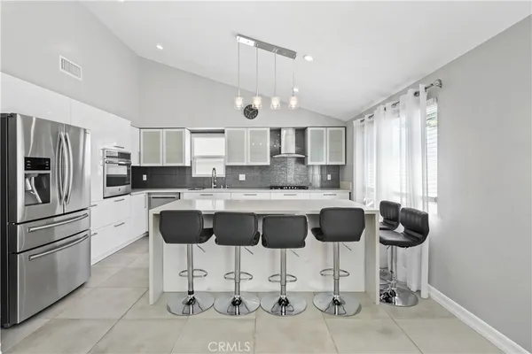 a kitchen with stainless steel appliances granite countertop a refrigerator a stove a sink a dining table and chairs