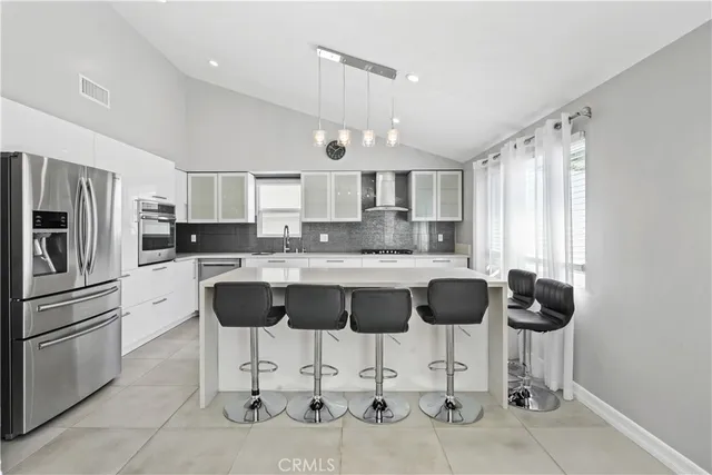 a kitchen with stainless steel appliances granite countertop a refrigerator a stove a sink a dining table and chairs