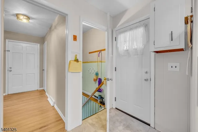 a view of an empty room with wooden floor kitchen view and a window