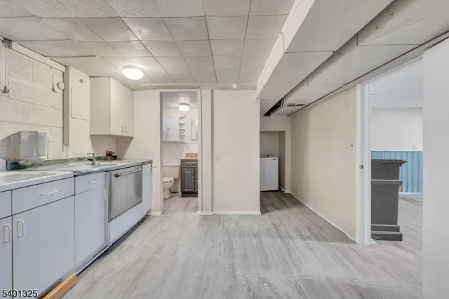 a kitchen with granite countertop a refrigerator oven a sink and white cabinets