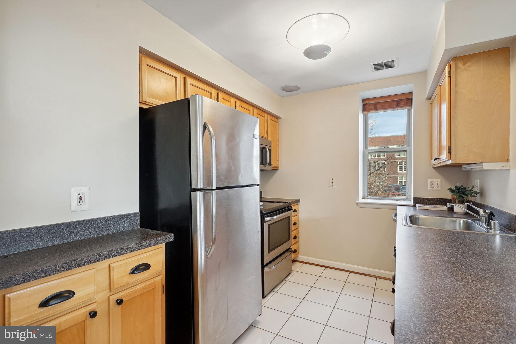 1308 Clifton Street Northwest, Unit 104 Washington, DC 20009 - Photo 10 of 24 a kitchen with a refrigerator a stove a washer and dryer