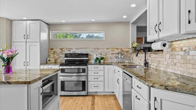 a kitchen with stainless steel appliances granite countertop a stove a sink and a microwave