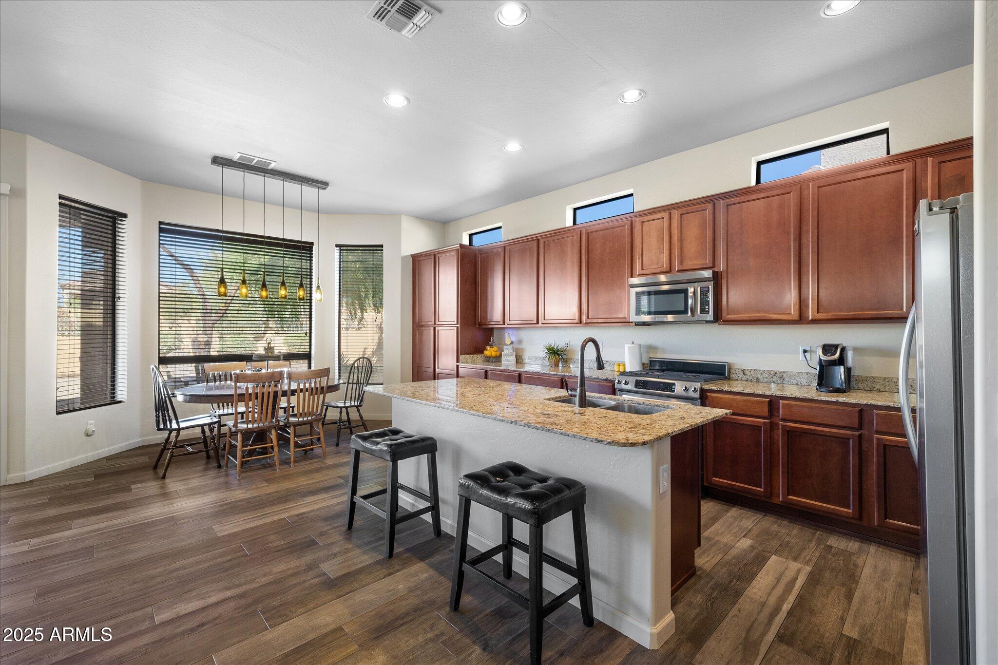 8536 East Inca Street Mesa, AZ 85207 - Photo 3 of 44 a kitchen with stainless steel appliances granite countertop a stove top oven a sink dishwasher a dining table and chairs with wooden floor