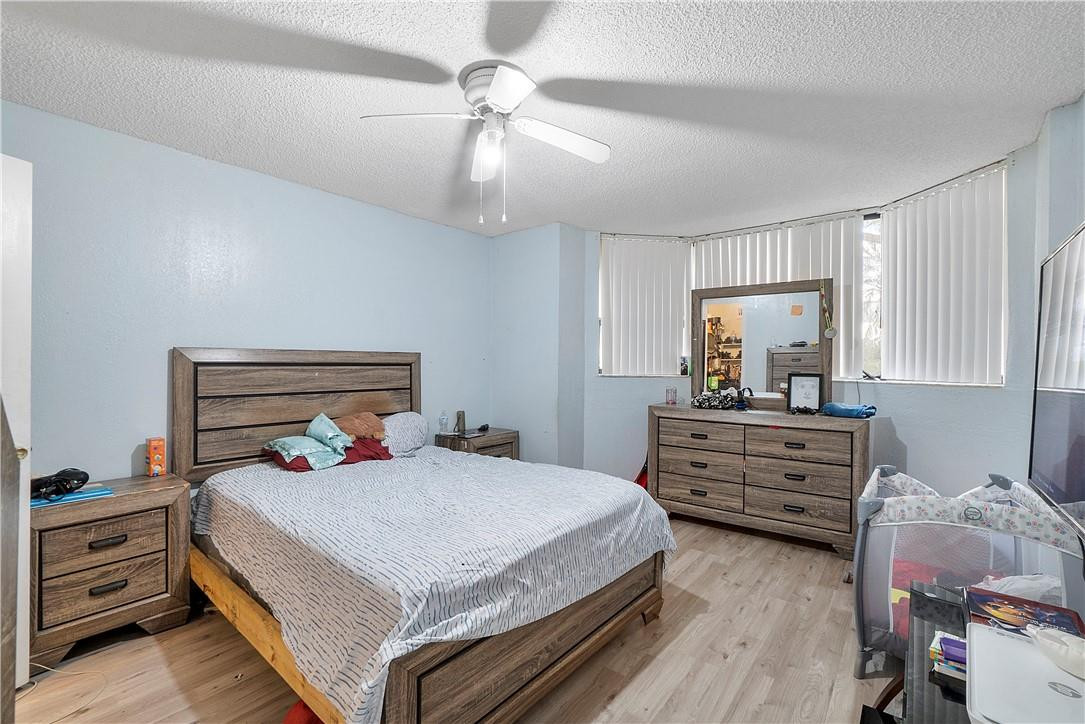 7401 Northwest 16th Street, Unit 103 Plantation, FL 33313 - Photo 7 of 12 a bedroom with a bed and a chandelier