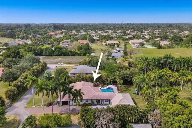 an aerial view of residential houses with outdoor space and trees