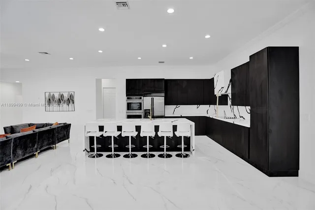 a kitchen with stainless steel appliances kitchen island granite countertop a refrigerator and a sink