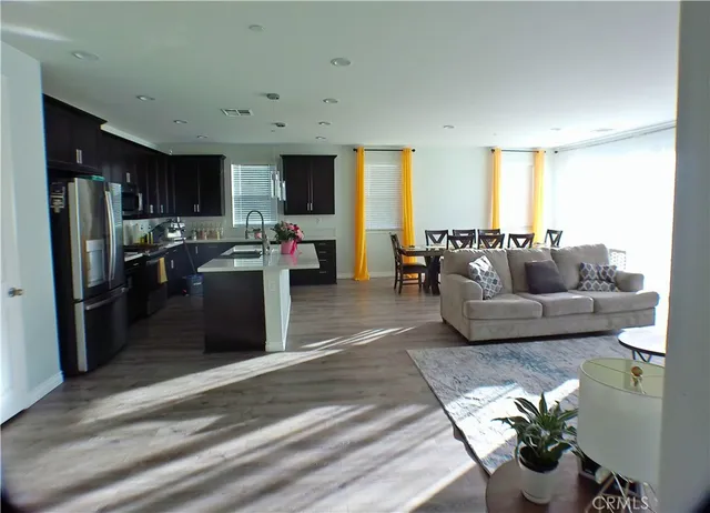 a living room with stainless steel appliances furniture and a view of kitchen
