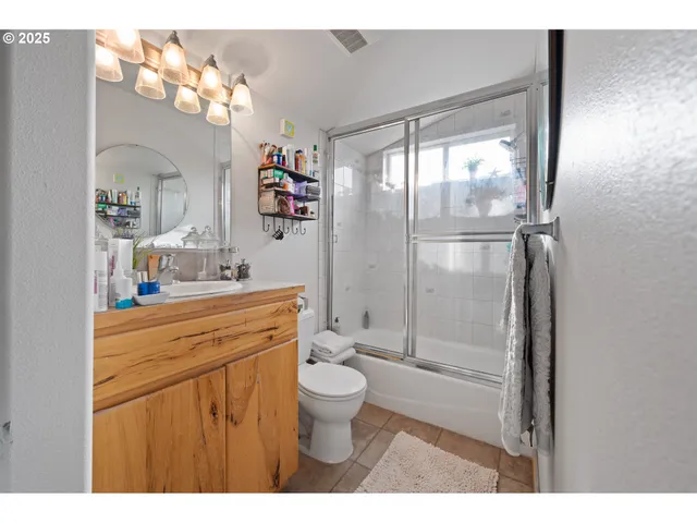 a bathroom with a granite countertop sink toilet mirror and a shower