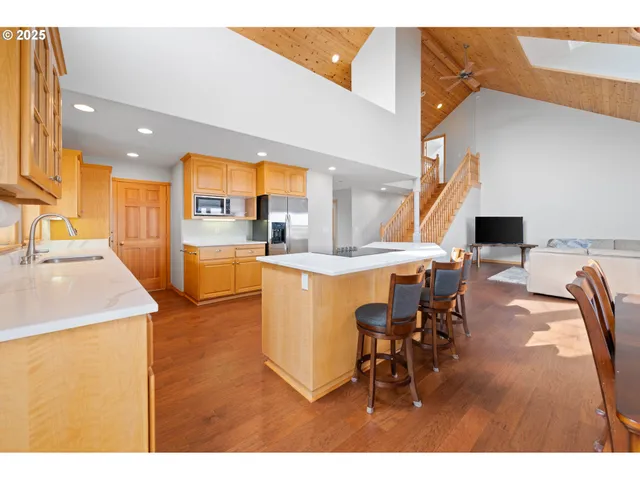 a dining hall with stainless steel appliances kitchen island granite countertop a dining table chairs and a kitchen view