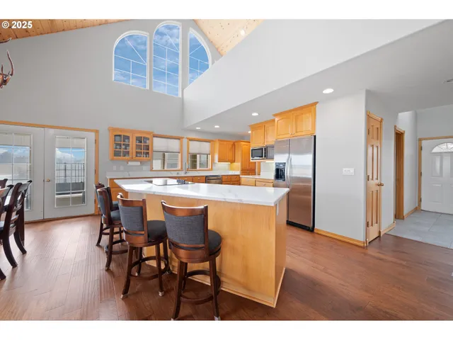 a dining hall with stainless steel appliances kitchen island a table and chairs