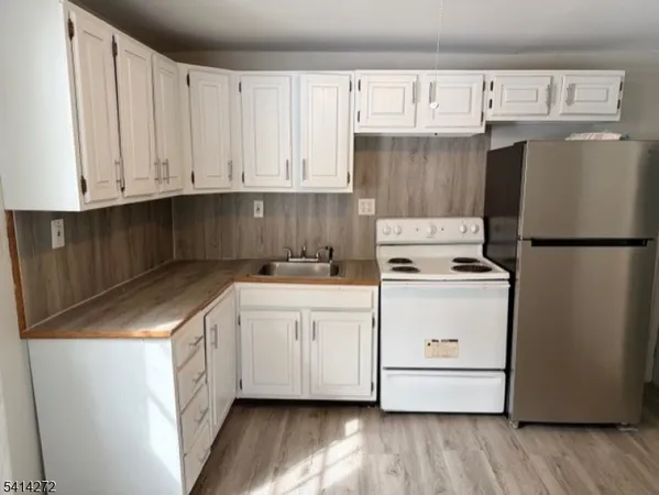 a kitchen with stainless steel appliances white cabinets and wooden floors