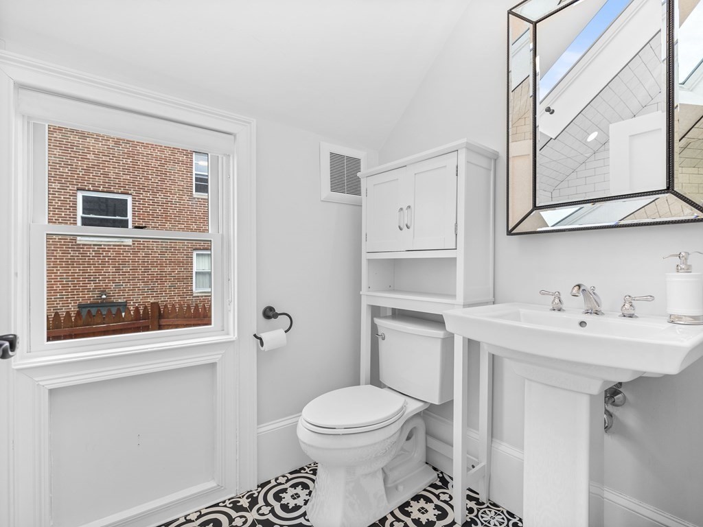 131 Centre Street Boston, MA 02124 - Photo 18 of 26 a bathroom with a toilet a sink a vanity and mirror