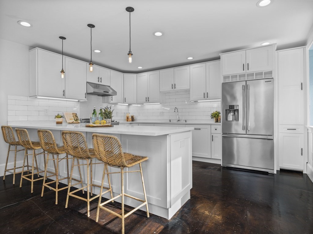 131 Centre Street Boston, MA 02124 - Photo 6 of 26 a kitchen with stainless steel appliances granite countertop a refrigerator a stove a sink a dining table and chairs with wooden floor