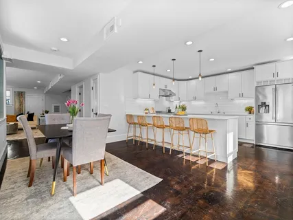 a kitchen with stainless steel appliances kitchen island granite countertop a dining table chairs and white cabinets