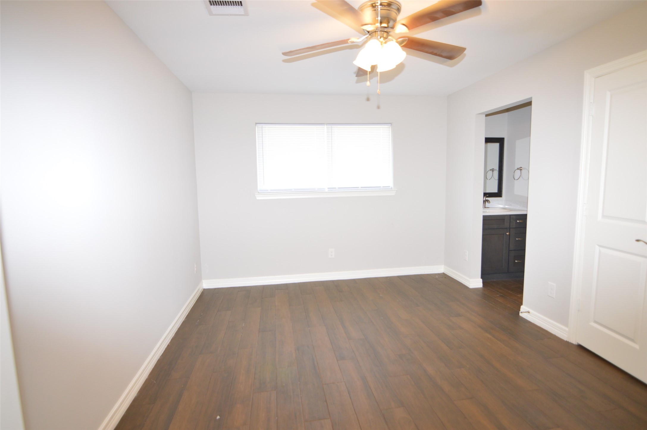 10002 Neuens Road, Unit 2 Houston, TX 77080 - Photo 7 of 15 an empty room with wooden floor chandelier fan and windows