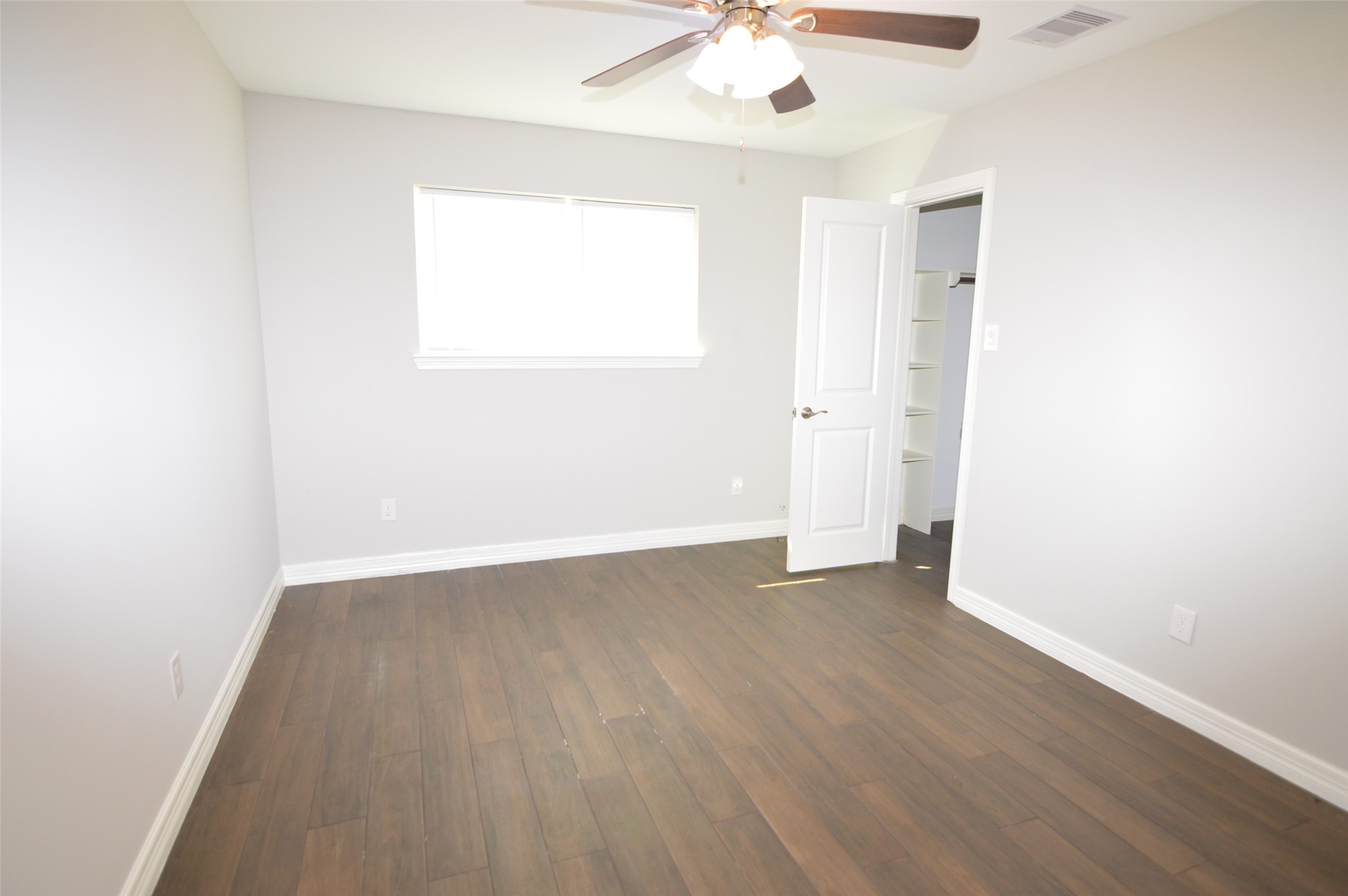 10002 Neuens Road, Unit 2 Houston, TX 77080 - Photo 10 of 15 an empty room with wooden floor chandelier fan and windows