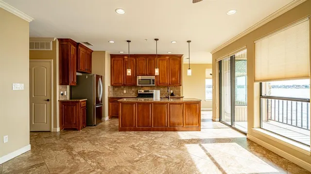 a kitchen with stainless steel appliances kitchen island granite countertop a refrigerator and a sink