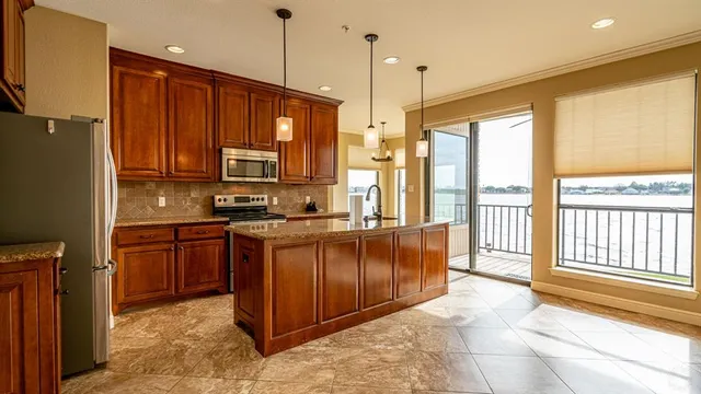 a kitchen with stainless steel appliances granite countertop a refrigerator a oven a sink with a dining table and chairs