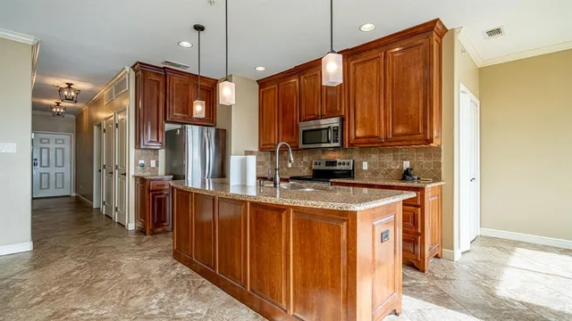 a view of kitchen with stainless steel appliances granite countertop a refrigerator and a stove top oven