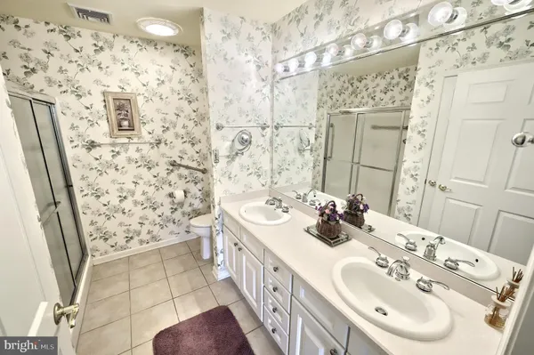 a bathroom with double vanity sink a mirror and shower
