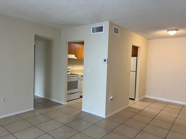 a view of a refrigerator in kitchen and an empty room