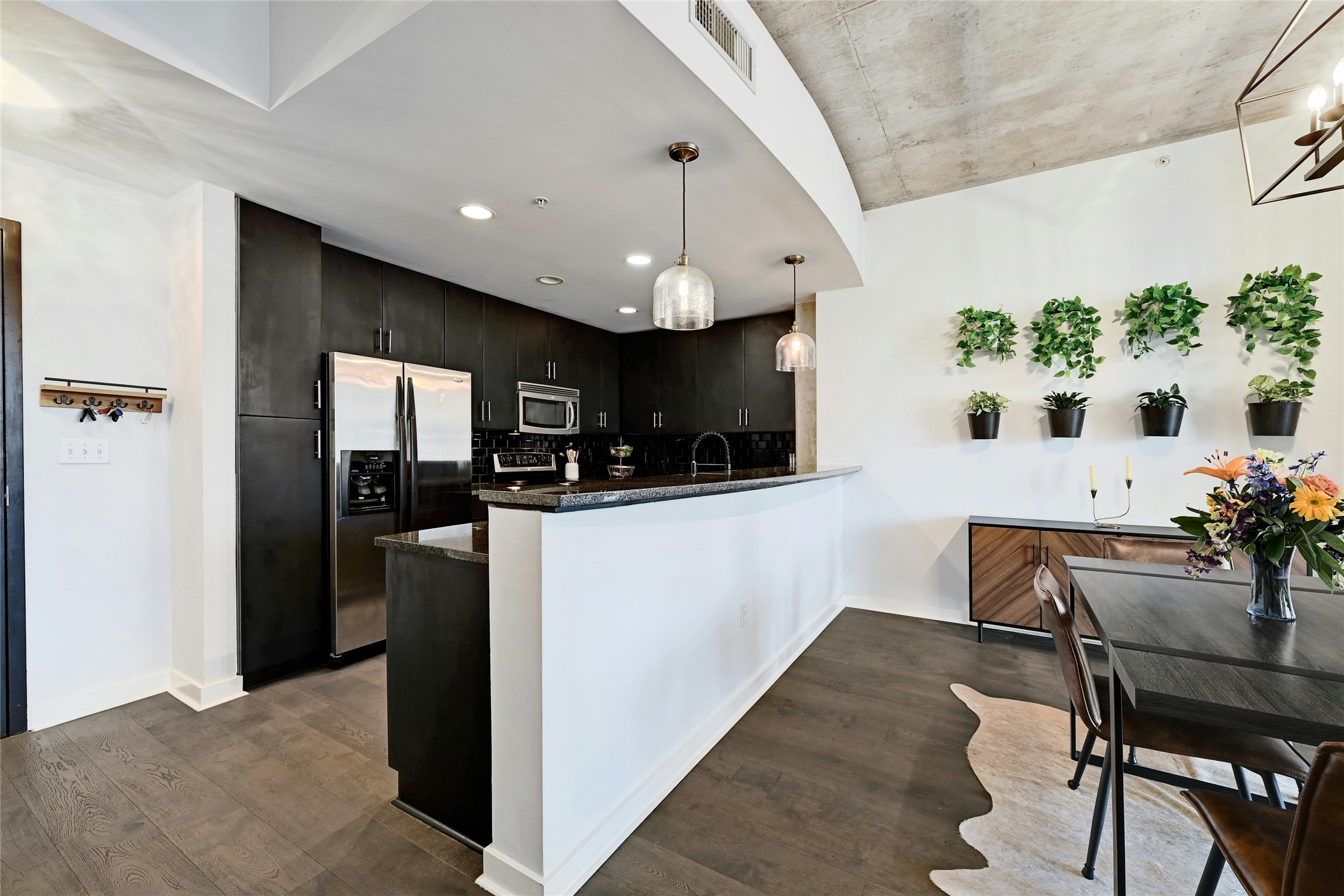 360 Nueces Street, Unit 1809 Austin, TX 78701 - Photo 9 of 25 Contemporary kitchen and dining area featuring dark wood-finish cabinetry, stainless steel appliances, and wood-finish flooring