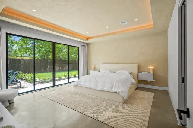 a bed sitting in a spacious bedroom next to a window