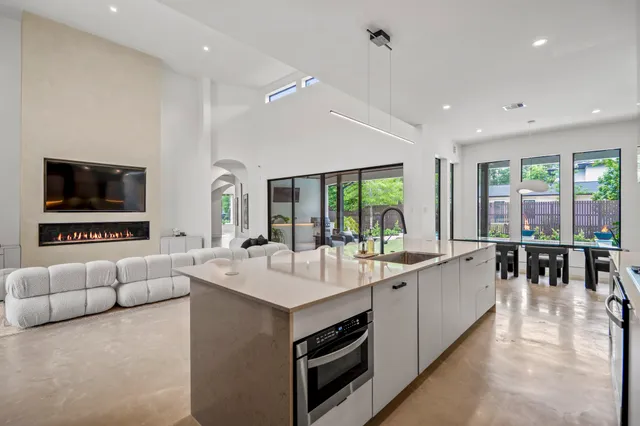 a large white kitchen with furniture a large window and a flat screen tv