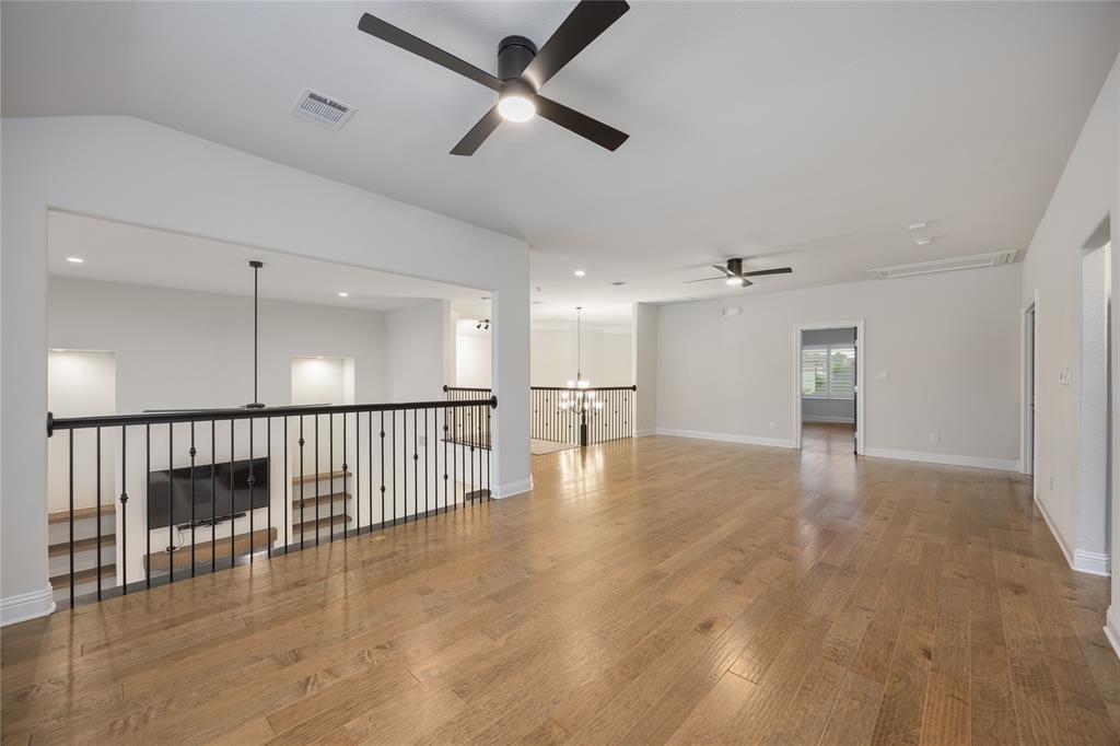 918 Sydney Lane Allen, TX 75013 - Photo 22 of 40 Expansive living area with hardwood floors, contemporary ceiling fans, and a black wrought iron railing overlooking the lower level