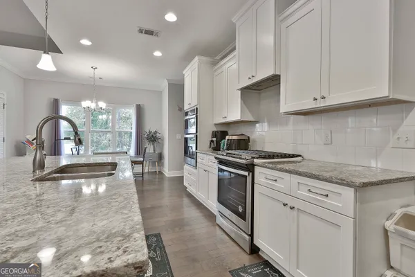 a kitchen with a stove a sink a dining table and chairs
