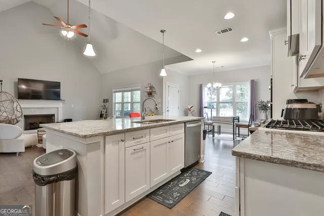 a kitchen that has a lot of white cabinets and stainless steel appliances