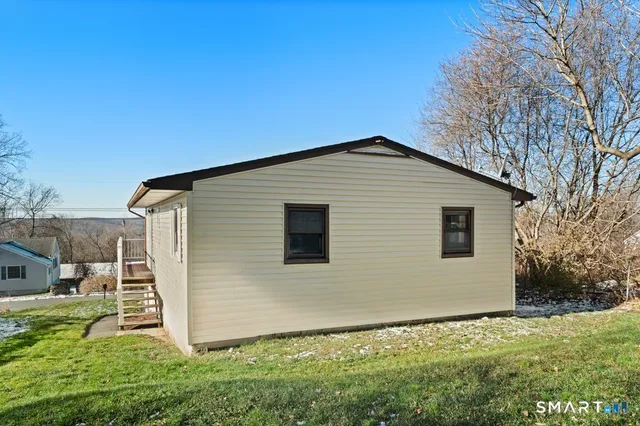 a backyard of a house with plants and large tree