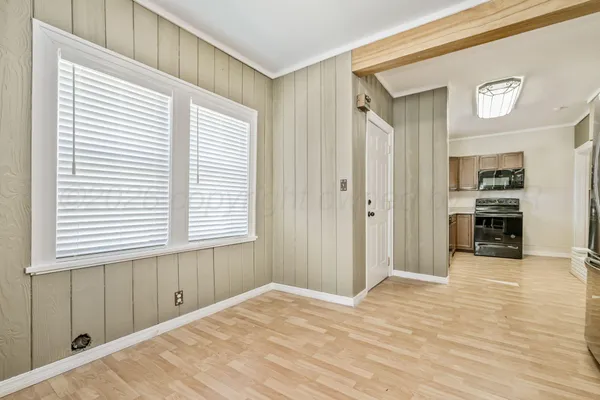 a view of an empty room with kitchen and a window