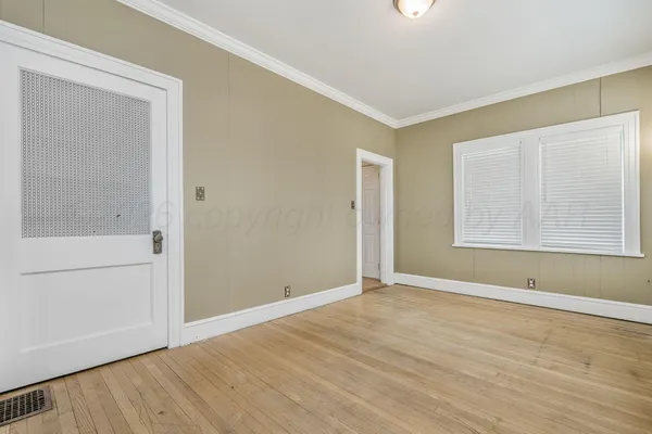 a view of an empty room with wooden floor and a window